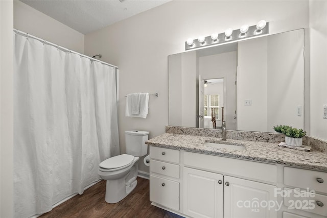 bathroom with ceiling fan, vanity, wood finished floors, and toilet