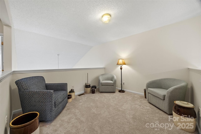 sitting room with vaulted ceiling, a textured ceiling, carpet, and baseboards