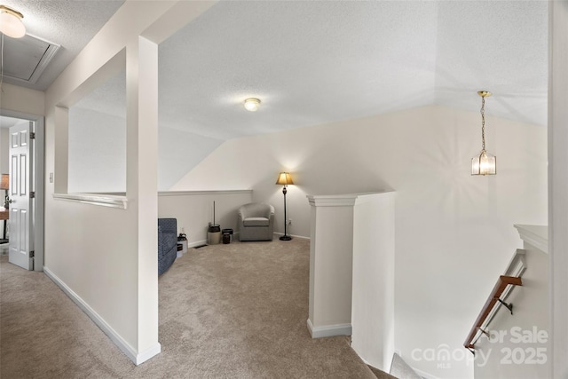 additional living space featuring carpet floors, attic access, vaulted ceiling, and a textured ceiling