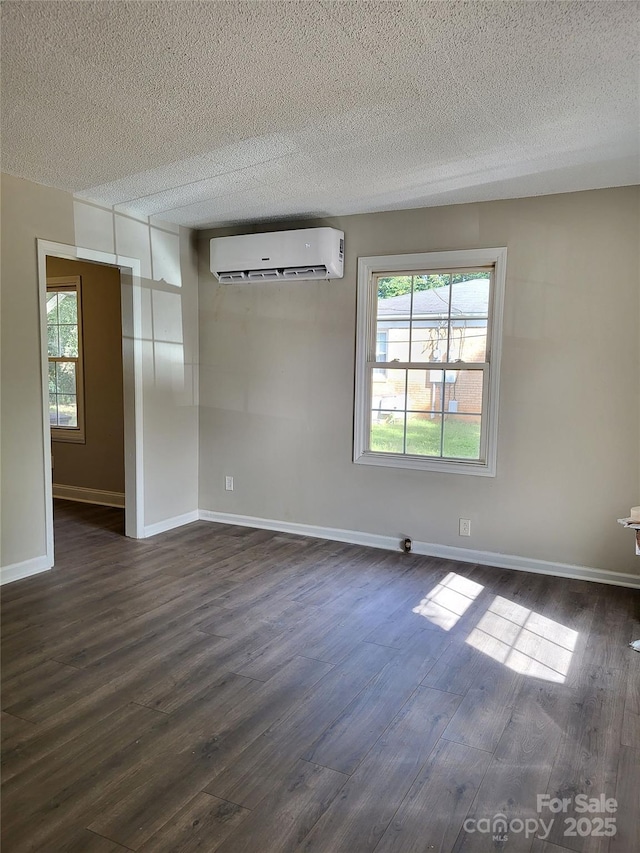 unfurnished room with dark wood-style flooring, a wall mounted air conditioner, and plenty of natural light