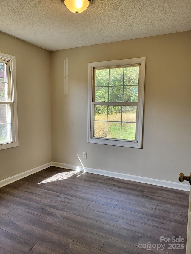 empty room with baseboards, dark wood finished floors, and a healthy amount of sunlight