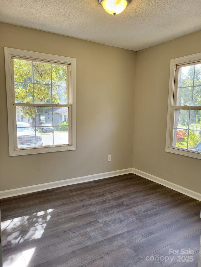 spare room with a textured ceiling, dark wood finished floors, and baseboards