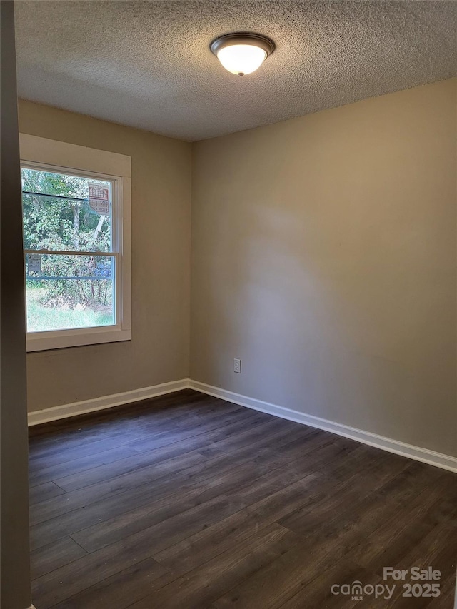 unfurnished room with a textured ceiling, baseboards, and dark wood-type flooring