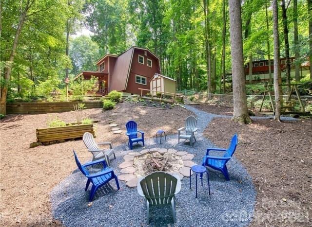 view of patio with an outdoor fire pit, fence, and an outdoor structure