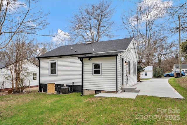 rear view of property featuring cooling unit, a patio, crawl space, a shingled roof, and a lawn