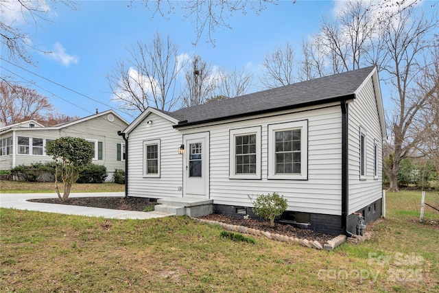 view of front of home with crawl space, roof with shingles, and a front yard