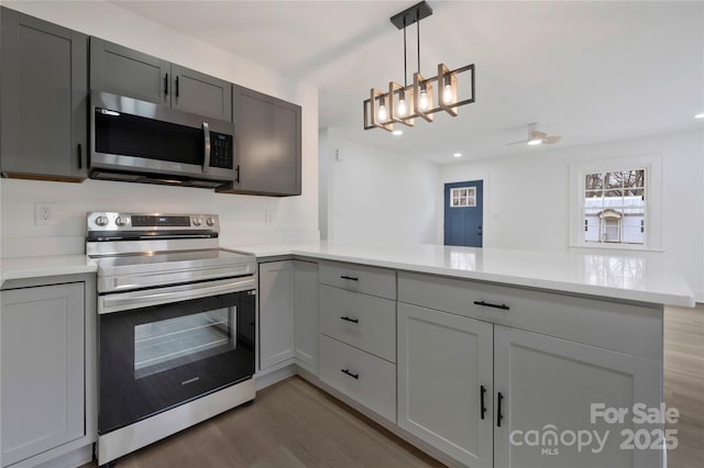 kitchen featuring light countertops, a peninsula, appliances with stainless steel finishes, and light wood finished floors