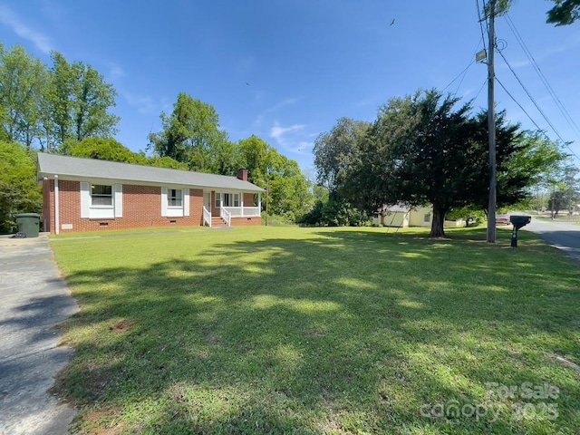 ranch-style house featuring crawl space, a chimney, a front lawn, covered porch, and brick siding