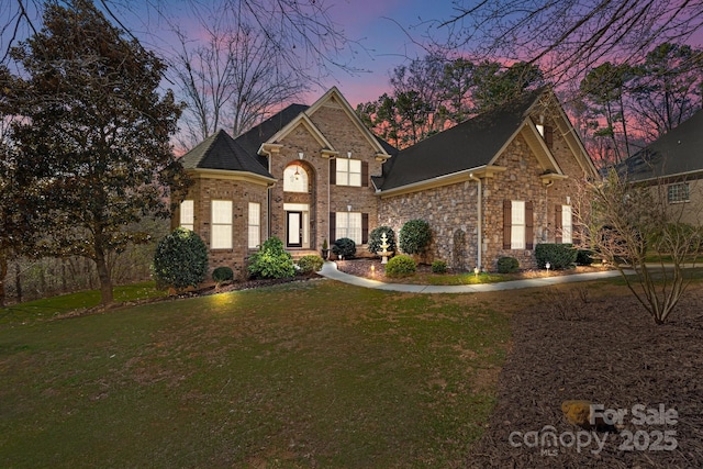 view of front of house featuring brick siding and a yard