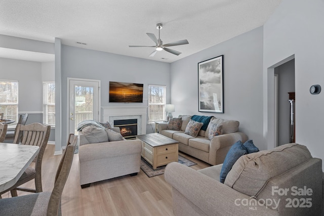 living room featuring a premium fireplace, plenty of natural light, visible vents, and light wood-style floors