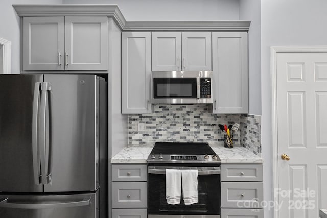 kitchen featuring light stone countertops, tasteful backsplash, stainless steel appliances, and gray cabinetry