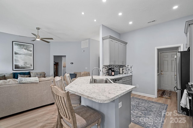 kitchen with a peninsula, a sink, visible vents, and gray cabinetry