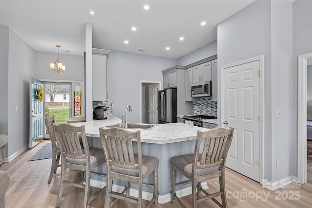 kitchen featuring appliances with stainless steel finishes, a peninsula, gray cabinets, light countertops, and backsplash