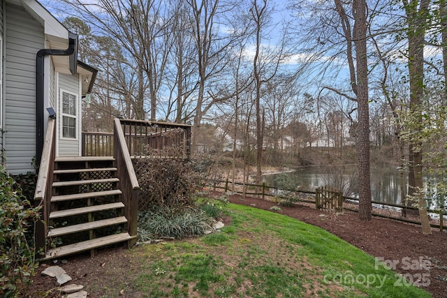 view of yard featuring stairs and a deck with water view