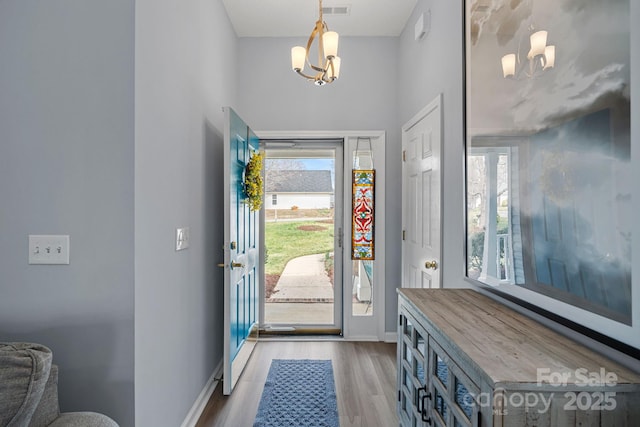 entryway with a chandelier, visible vents, light wood-type flooring, and baseboards