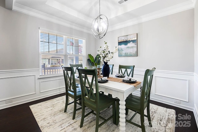 dining area featuring ornamental molding, wainscoting, a chandelier, and dark wood-type flooring