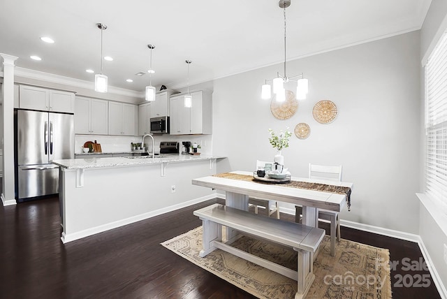 kitchen with a sink, a peninsula, ornamental molding, and stainless steel appliances
