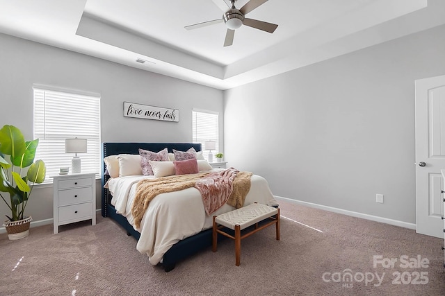 bedroom with carpet floors, baseboards, and a tray ceiling