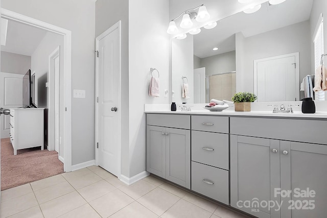 bathroom with double vanity, baseboards, an enclosed shower, tile patterned floors, and a sink