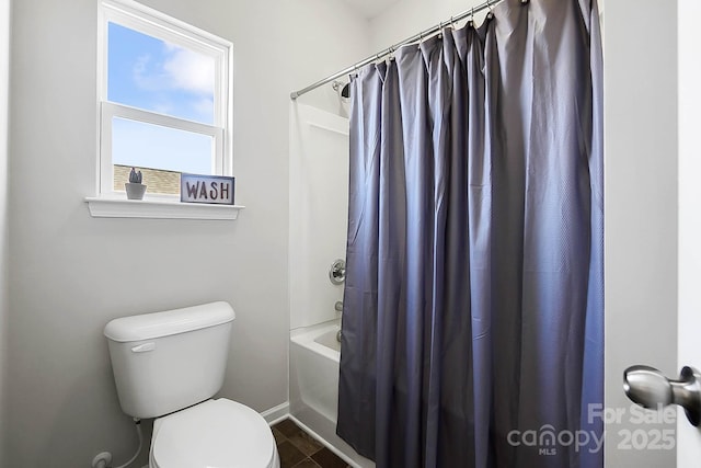 bathroom featuring baseboards, shower / bath combo, and toilet