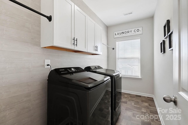 laundry area with stone finish floor, independent washer and dryer, visible vents, cabinet space, and baseboards