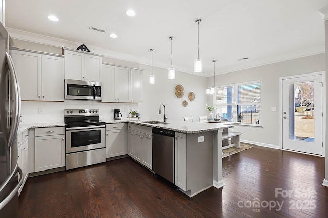 kitchen featuring dark wood-style flooring, light stone countertops, a peninsula, ornamental molding, and stainless steel appliances