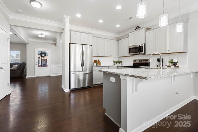 kitchen with a kitchen breakfast bar, appliances with stainless steel finishes, hanging light fixtures, a sink, and a peninsula
