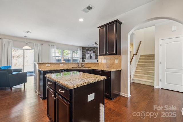 kitchen featuring dark wood finished floors, visible vents, a sink, and decorative backsplash