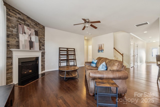 living room with baseboards, visible vents, a glass covered fireplace, ceiling fan, and wood finished floors