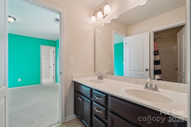 full bath with double vanity, a sink, visible vents, and baseboards