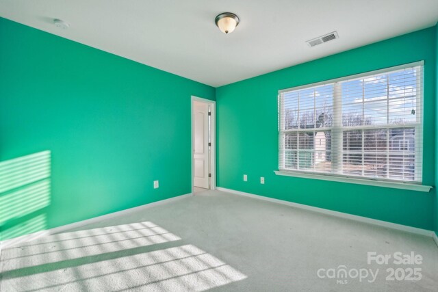 carpeted empty room with visible vents and baseboards