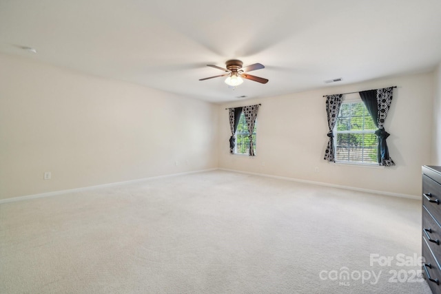 unfurnished room featuring baseboards, visible vents, a wealth of natural light, and light colored carpet