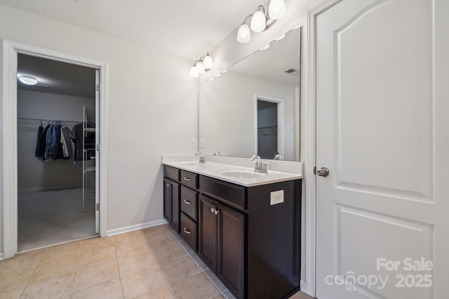 bathroom featuring double vanity, tile patterned flooring, baseboards, and a sink