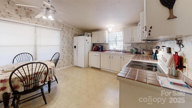 kitchen featuring white appliances, white cabinetry, tile countertops, and wallpapered walls