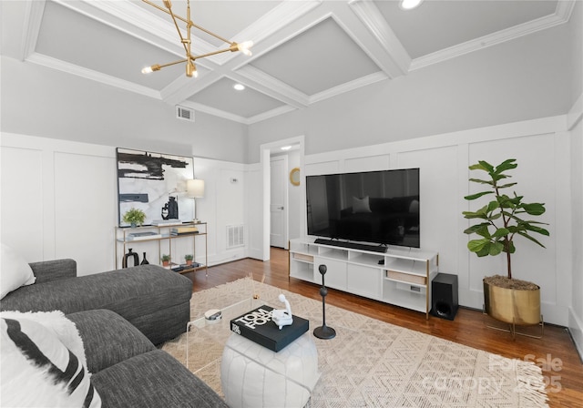 living area featuring beam ceiling, visible vents, a decorative wall, wood finished floors, and coffered ceiling