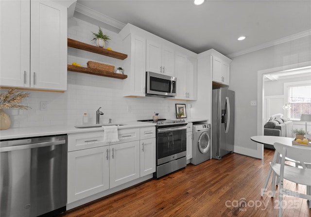 kitchen with light countertops, appliances with stainless steel finishes, ornamental molding, a sink, and washer / dryer