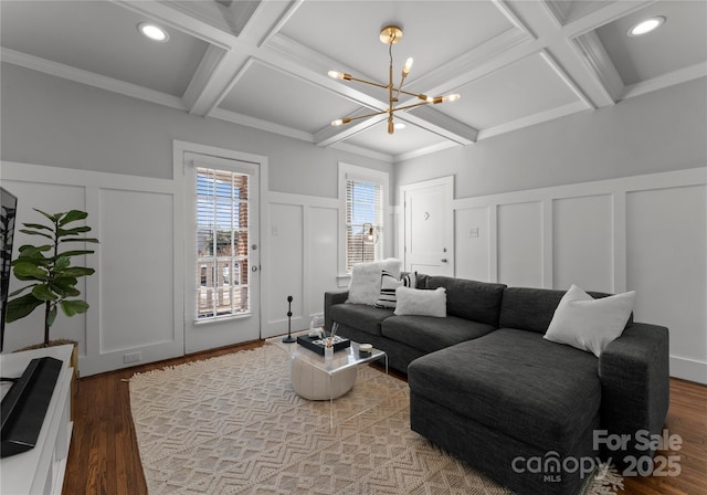 living room featuring coffered ceiling, beam ceiling, a decorative wall, and a notable chandelier