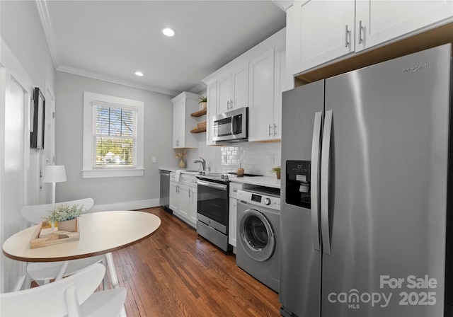 kitchen with decorative backsplash, appliances with stainless steel finishes, washer / clothes dryer, ornamental molding, and a sink