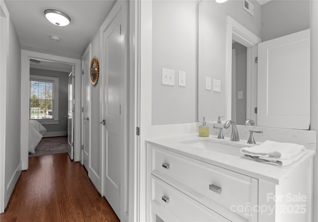 bathroom with baseboards, visible vents, wood finished floors, and vanity