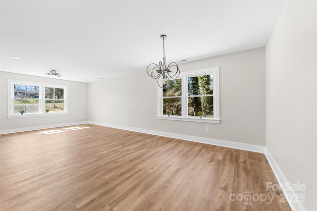 unfurnished room featuring light wood-style floors, baseboards, and a chandelier