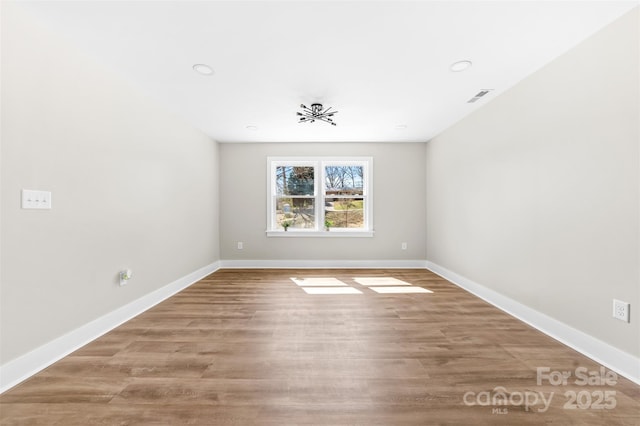 empty room with visible vents, light wood-style flooring, and baseboards