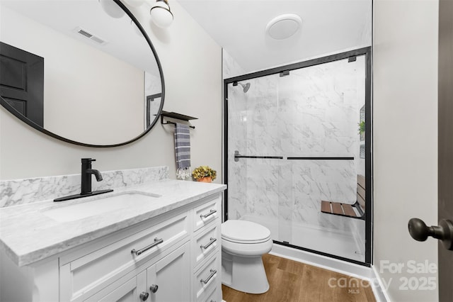 full bath with toilet, a stall shower, visible vents, and wood finished floors