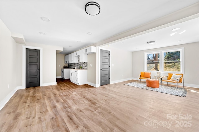 unfurnished living room with light wood-style flooring, baseboards, and a sink