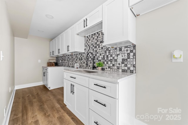 kitchen featuring dark wood-style flooring, light countertops, a sink, and backsplash