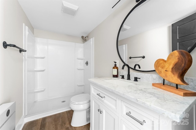 bathroom with toilet, wood finished floors, visible vents, vanity, and a shower