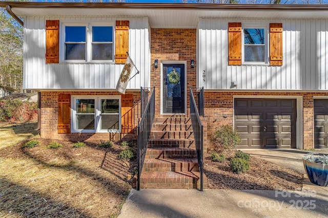 view of front of home featuring driveway, a garage, and brick siding