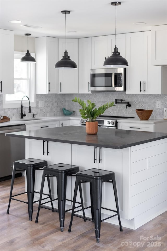 kitchen featuring backsplash, appliances with stainless steel finishes, white cabinets, and a sink