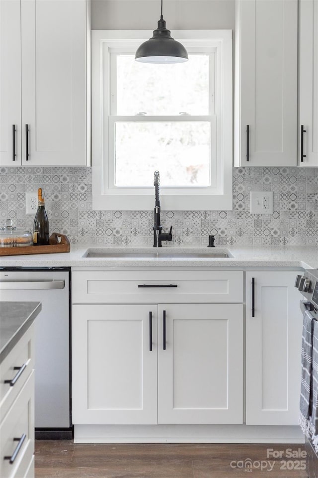 kitchen featuring appliances with stainless steel finishes, white cabinets, a sink, and tasteful backsplash