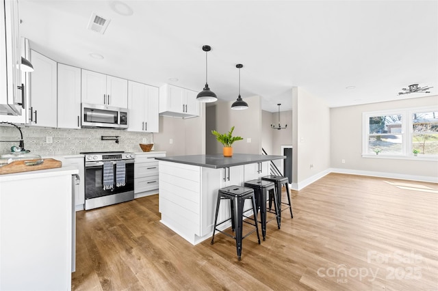 kitchen with a breakfast bar area, visible vents, backsplash, appliances with stainless steel finishes, and white cabinets