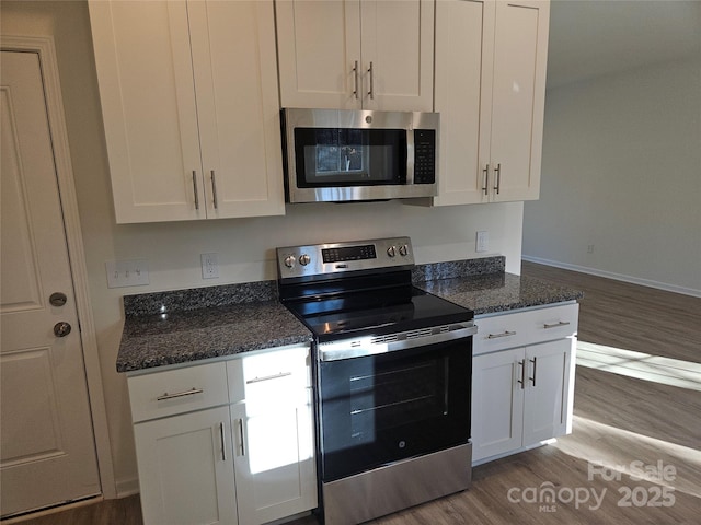 kitchen featuring appliances with stainless steel finishes, dark wood-style flooring, white cabinetry, and dark stone countertops